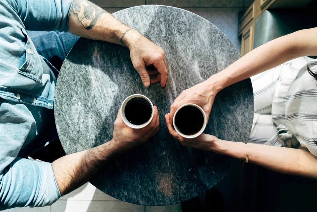 カフェのテーブルでコーヒーを手に語り合うふたり